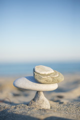 Sculpture made with stack stones in equilibrium close to the shore on a sandy beach.
