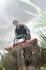 Farmer using rototiller in field