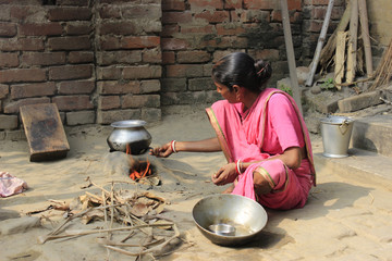 Cooking. A woman is cooking rice in a remote village. Food is our necessity. The woman is cooking rice with the help of natural equipment.