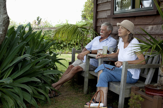Senior couple relaxing by wooden cabin, Raglan, New Zealand