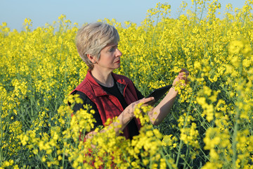 Fototapeta premium Farmer or agronomist examine rapeseed field, using tablet