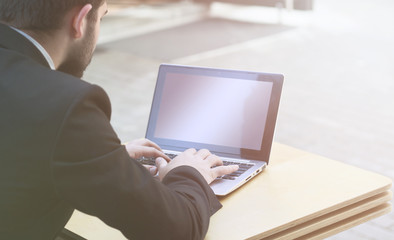 Closeup toned image of businessman using laptop computer. Blank screen may be used for many biusiness ideas, concepts, strategies, projects, etc.