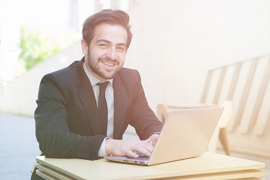Toned portrait of handsome businessman sitting n cafe aor restaurant and working on laptop computer upon different business projects and strategies.