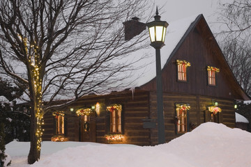 Reconstructed 1840s residential log home with Christmas decorations at dusk, Quebec, Canada