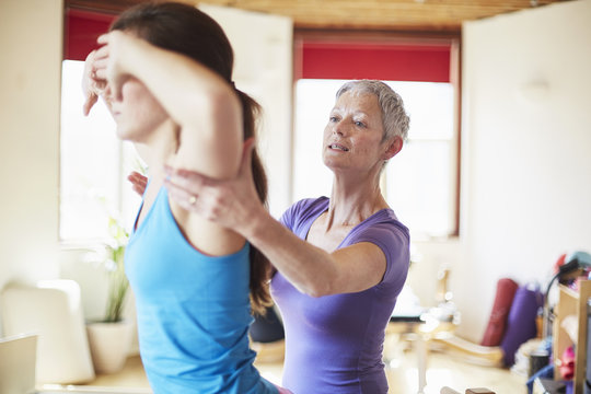 Young female student and tutor in pilates gym