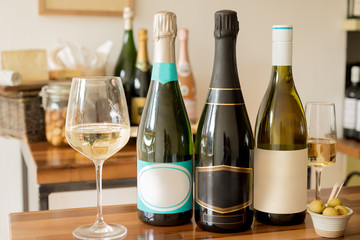 Bottles of Champagne with Blank Labels Between Wineglasses and O