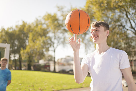 Smiling young male basketball player balancing basketball on finger