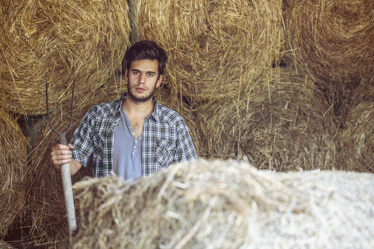 Portrait of young male farmer in straw barn with pitchfork, Premosello, Verbania, Piemonte, Italy