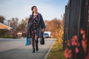 Happy brunette in a dress coat and goes shopping down the street