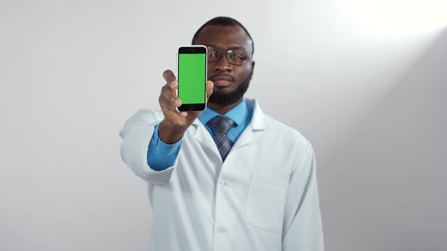 African american male doctor showing smart phone green screen