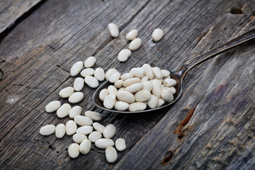 Fototapeta na wymiar Navy beans on spoon, on wooden surface.