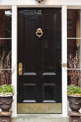 Black front door, with planters and a brass door knocker