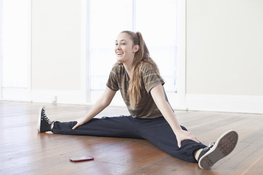 Teenage girl warming up and doing the splits in ballet school