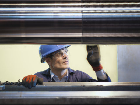 Engineer inspecting turned steel in engineering factory