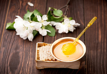Honeycomb and bowl with honey on a dark wooden background