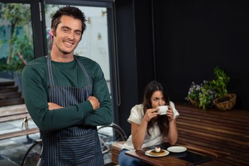 Smiling waiter posing with arms cross in front of client