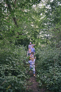 Fathers and sons playing chase in forest