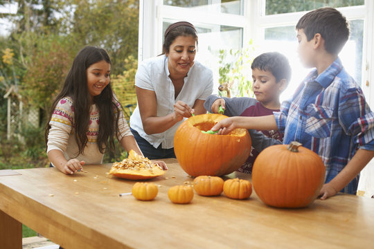 Mother and children carving pumpkin in dining room