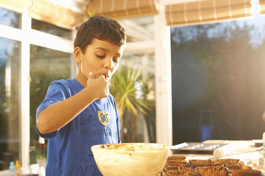 Boy tasting cake mixture in kitchen