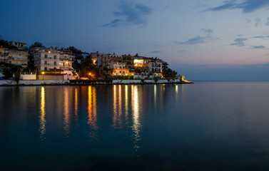 Greek island at dawn with calm peaceful relaxing sea water and reflections of lights on a beautiful night
