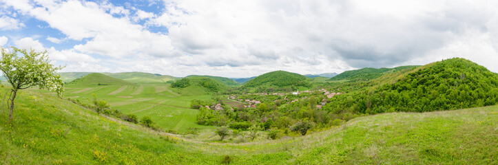 Fototapeta na wymiar Old small traditional village in a beautiful valley in Transylvania region of Romania. A beautiful wide panoramic perspective from abive with a small traditional rural settlement
