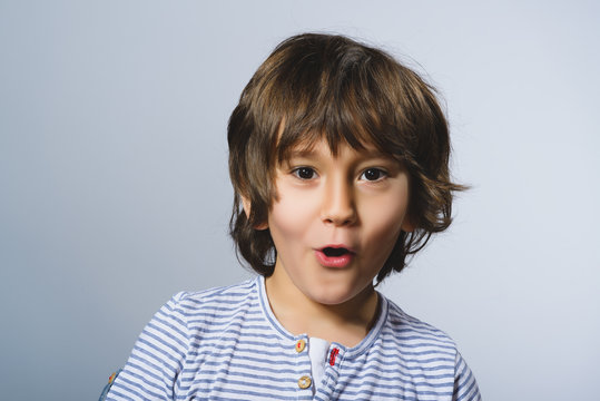 Closeup  Portrait of happy boy going surprise on gray background