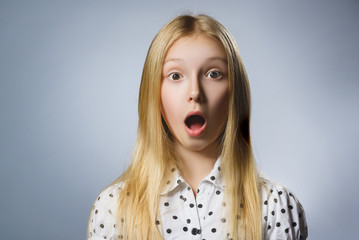  Closeup Portrait of handsome girl  with astonished expression while standing against grey...