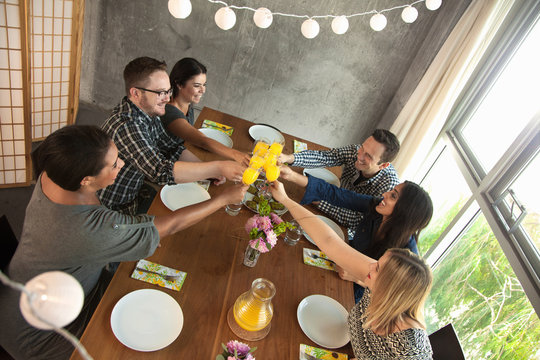Group of friends around table,  raising glasses, making toast