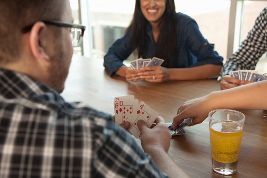 Group of friends playing cards around table