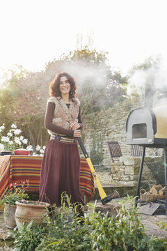 Portrait of mature hippy female with axe in garden