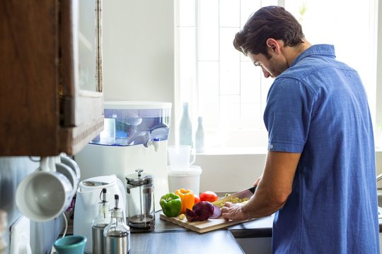 Man chopping vegetables at kitchen counter