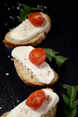 bread with cheese and cherry tomatoes on a dark background