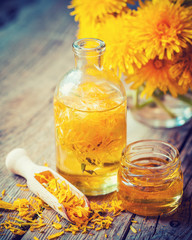 Bottle of dandelion tincture or oil, flower bunch and honey jar