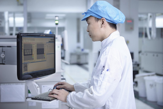 Worker using computer in factory that specialises in creating functional circuits on flexible surfaces