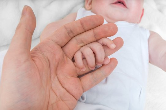 Adoption Baby Concept. Man Holds Little Child's Hand.