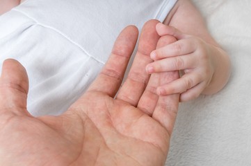 Father holds hand of his baby.