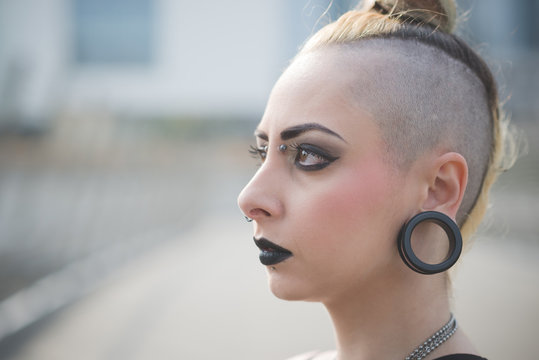 Portrait of young female punk with earlobe piercing and shaved head
