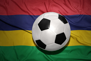 Naklejka premium black and white football ball on the national flag of mauritius