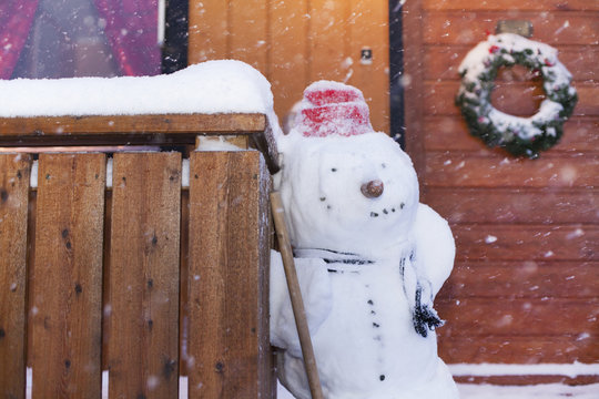 Snowman standing against wooden fence