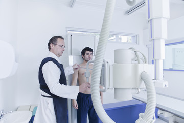 Radiographer preparing xray machine whilst patient standing