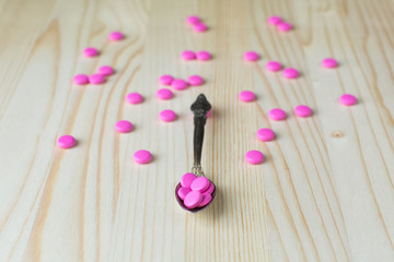 Pharmacy background. Full spoon of pills on a wooden table. Medicine. Natural background. Capsule on a spoon. Close up 