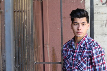 Handsome teenage boy in plaid shposing on edgy cool background with copy space for text message