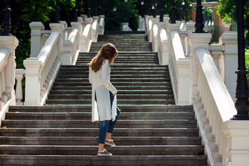 beautiful girl standing with her back on the stairs in the park