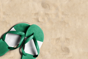 Fototapeta na wymiar Thongs with flag of Nigeria, on beach sand