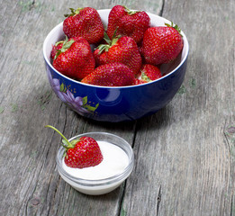 plate strawberry and one strawberry in a saucer with cream