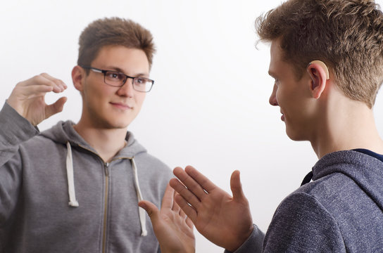 Two teenagers communicating with sign language, selective focus to the right.