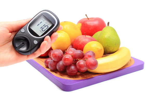 Hand of woman with glucose meter and fresh fruits