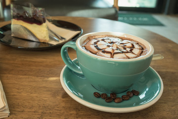 Hot coffee in green cup and saucer with silver spoon on wooden table / Hot coffee in white cup and saucer