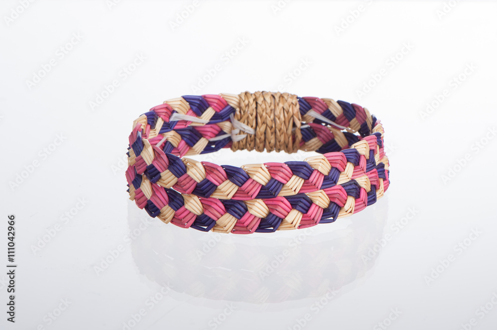 Wall mural wristband made from woven straw on a white background.