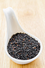 Black sesame seeds in white spoon.